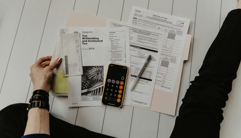 Financial professional reviewing tax and investment documents at desk with calculator and charts